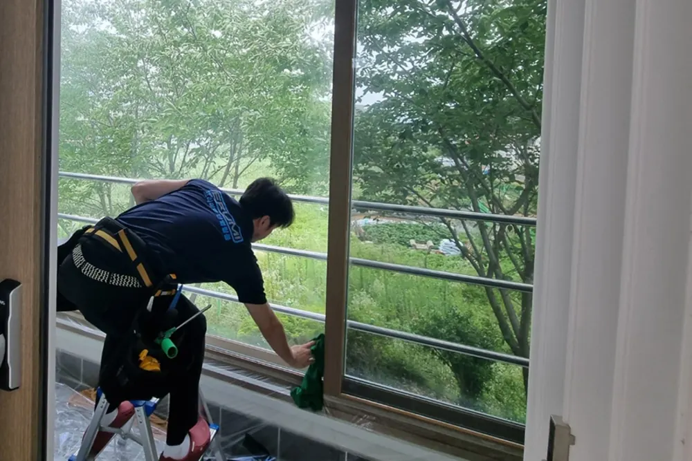 옥상 창호 유리 표면을 마감 청소하는 작업자
