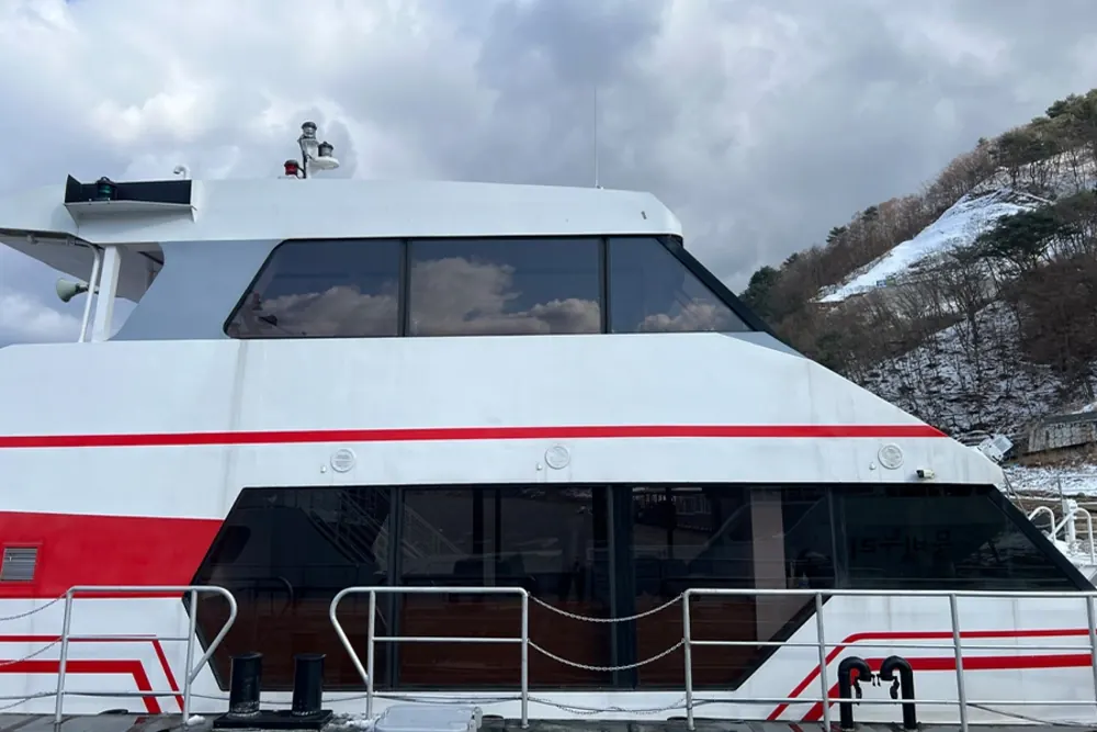 측면에서 본 유람선 전경, 눈 덮인 산과 선착장이 함께 보인다